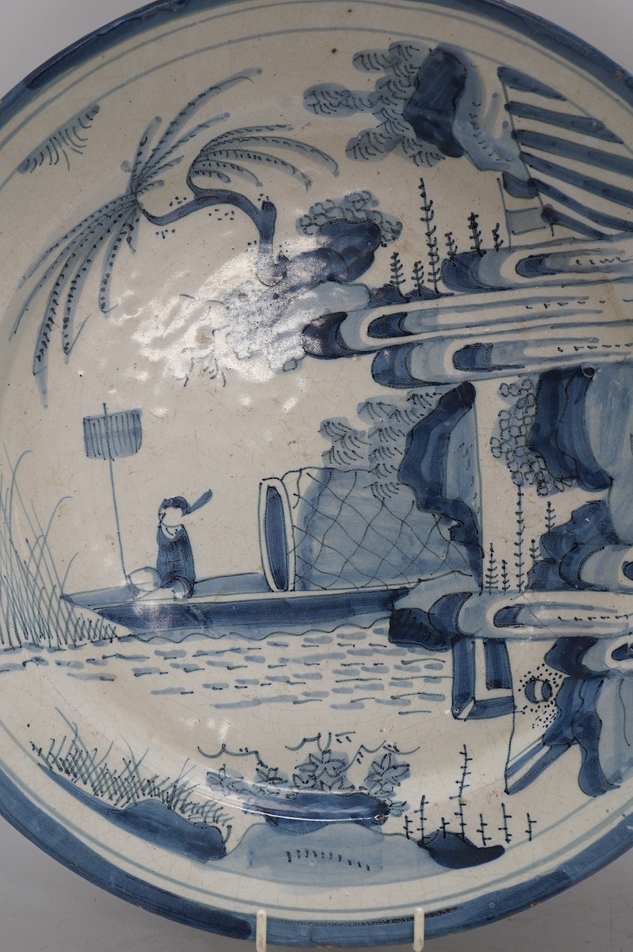 An 18th century Dutch Delft blue and white charger, diameter 33.5cm. Condition - poor, large crack running across half the diameter of the plate and through to the base, as well as some chips to the rim including one lar